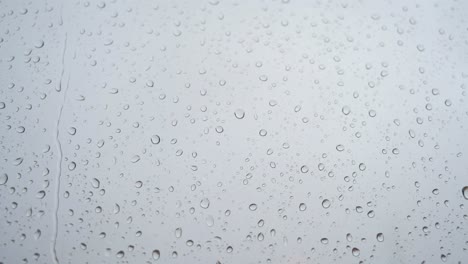 un metraje en cámara lenta de fuertes gotas de lluvia aterrizando en un vidrio de la ventana