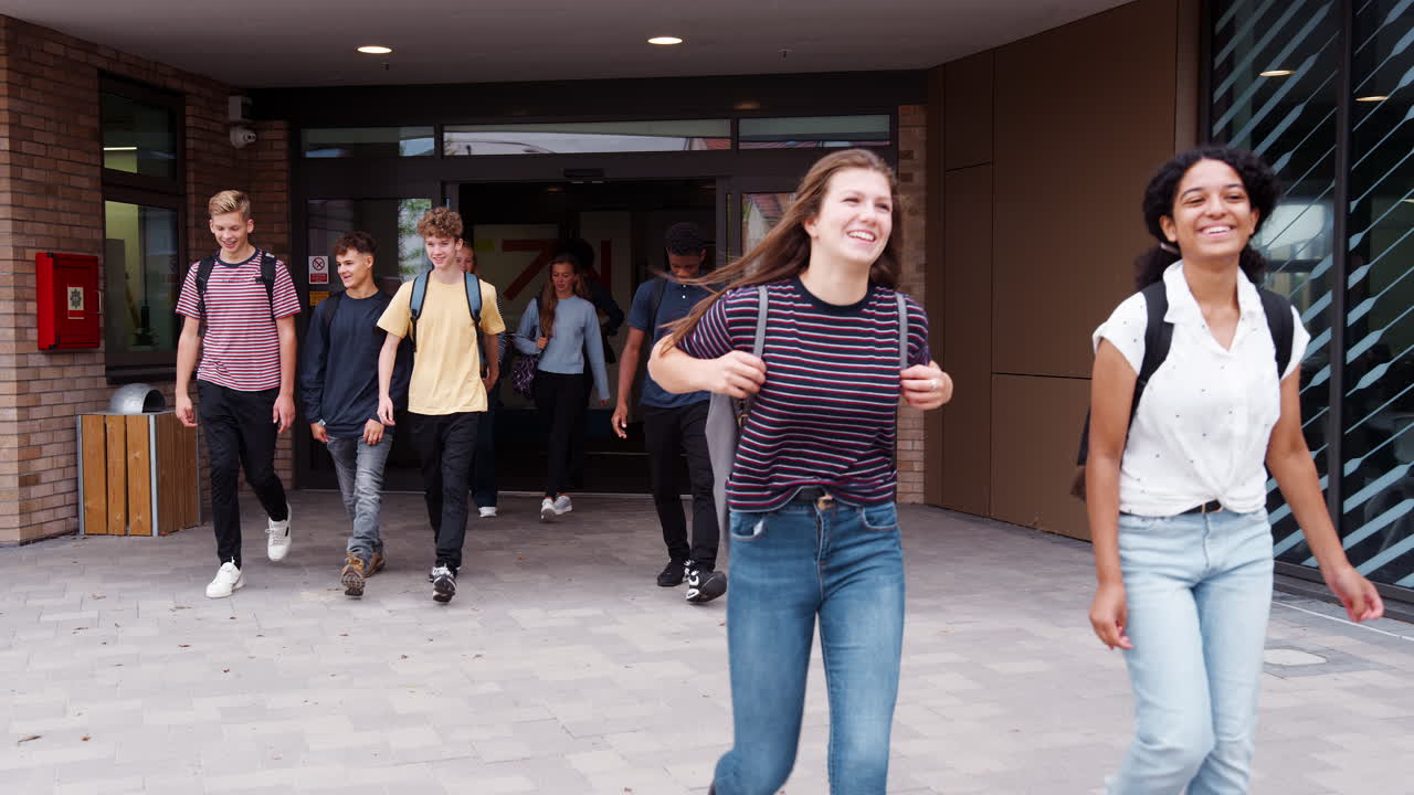 grupo de estudiantes de secundaria saliendo juntos del edificio de la universidad
