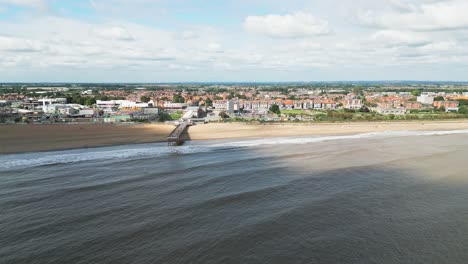 Típico-Balneario-Inglés,-Filmado-Con-Un-Dron-Volando-Hacia-El-Sol-Dando-Un-Punto-De-Vista-Aéreo-Con-Una-Amplia-Extensión-De-Playa-Con-Un-Muelle-Y-Olas-Rompientes-2