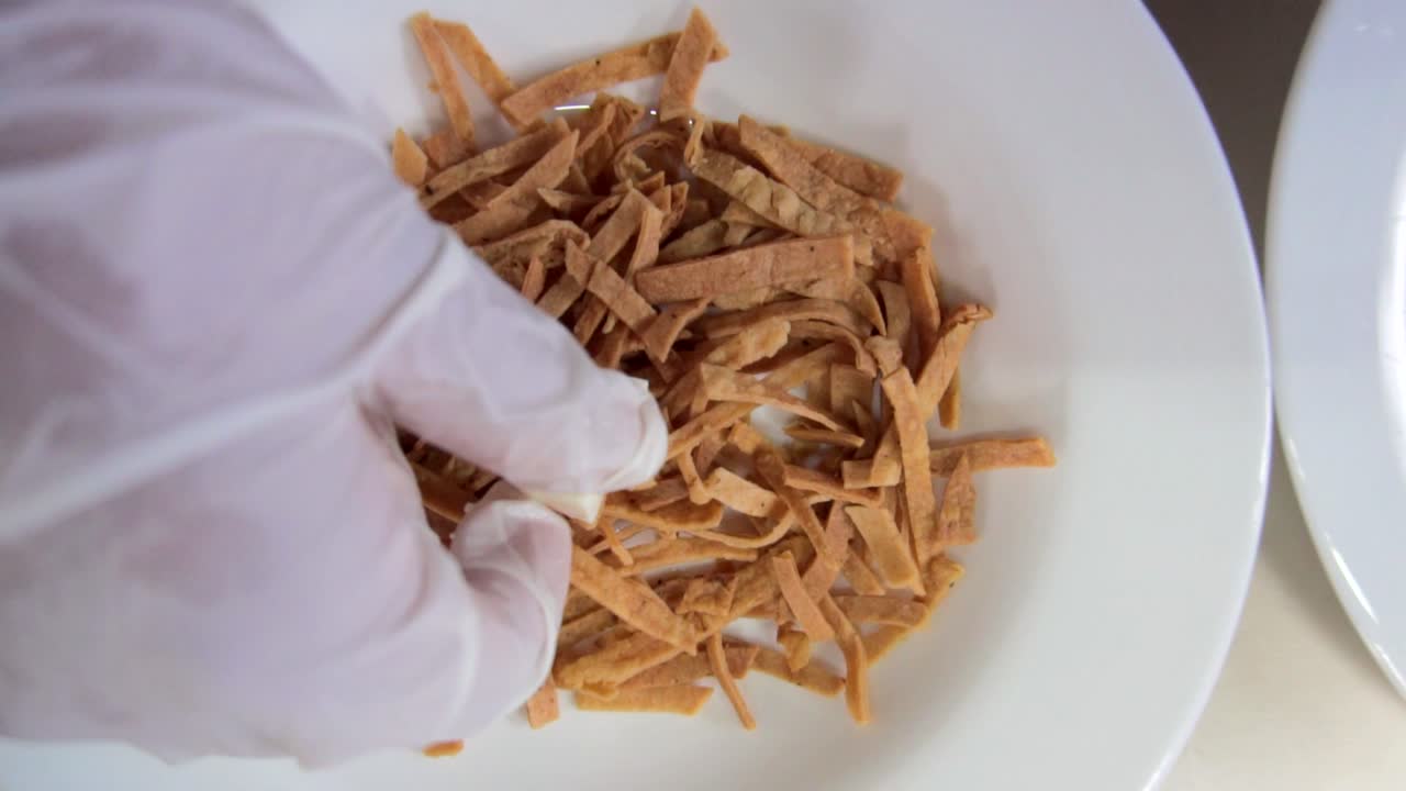 un tazón de chips de maíz y una mano que pone un cuadrado de queso