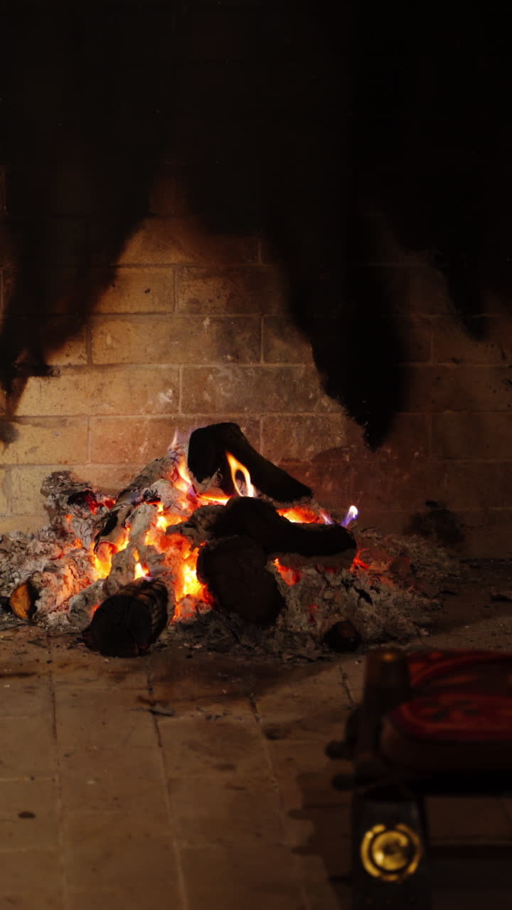 Romantic fire in fireplace. Smoldering logs on pile of ash in home mantel. Burning-out wooden logs. Burning wood in fireplace in winter. Vertical video