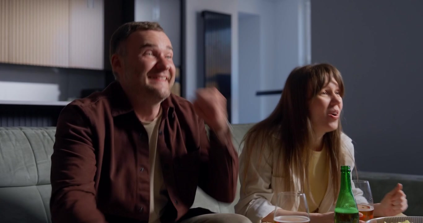 Entusiastisk par hepper og fejrer, mens de ser tv
