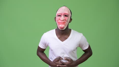 joven africano riendo mientras lleva una máscara y muestra el dedo medio