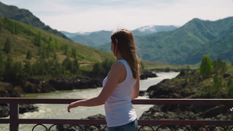 Mujer-Mira-A-Su-Alrededor-En-El-Puente-Sobre-El-Río-En-El-Valle-De-La-Montaña