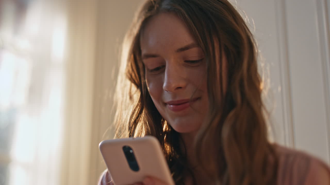 Ragazza gioiosa che legge un messaggio SMS alla luce del sole, in primo piano. Adolescente felice che usa il cellulare.