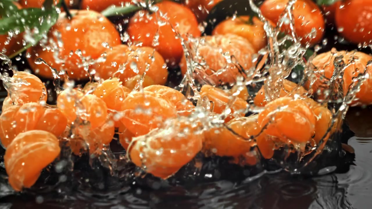 Slowmotion af friske mandarinskiver, der falder ned i vand