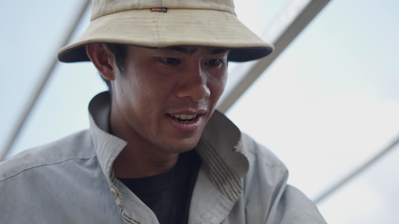 Close-up of a man in a bucket hat, possibly working outdoors.