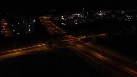 Winter-night-aerial:-Vehicle-traffic-on-highway-over,-underpasses