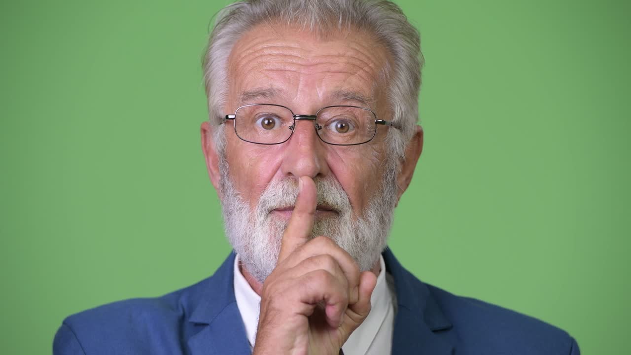 hombre de negocios barbudo y guapo contra un fondo verde.