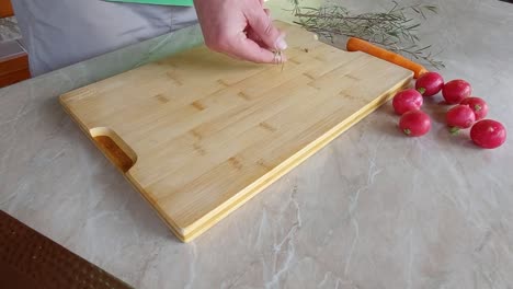 slicing fresh rosemary on wooden board with japanese ryukiri nikiri knife