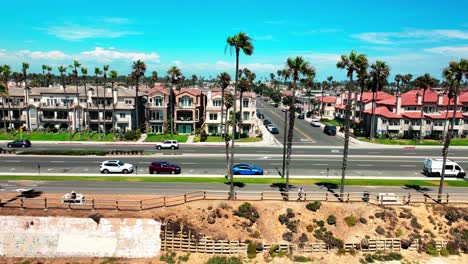 Panorámica-Hacia-La-Izquierda-Volando-Hacia-Abajo-Pch-En-Huntington-Beach,-California,-Con-Excelentes-Vistas-Del-Tráfico,-Palmeras,-El-Carril-Bici-Y-La-Autopista-De-La-Costa-Del-Pacífico