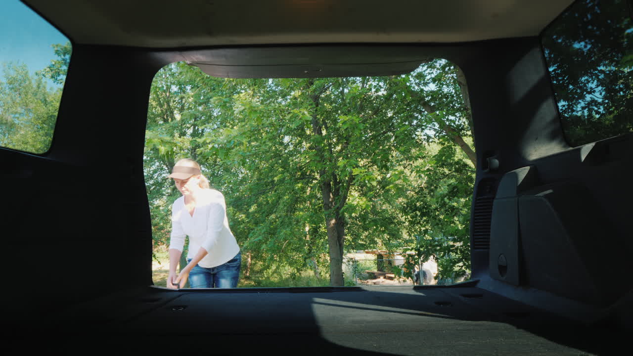 한 여성이 강아지와 함께 두 개의 우리를 자동차 트렁크에 넣고 애완 동물을 차량으로 운송합니다.