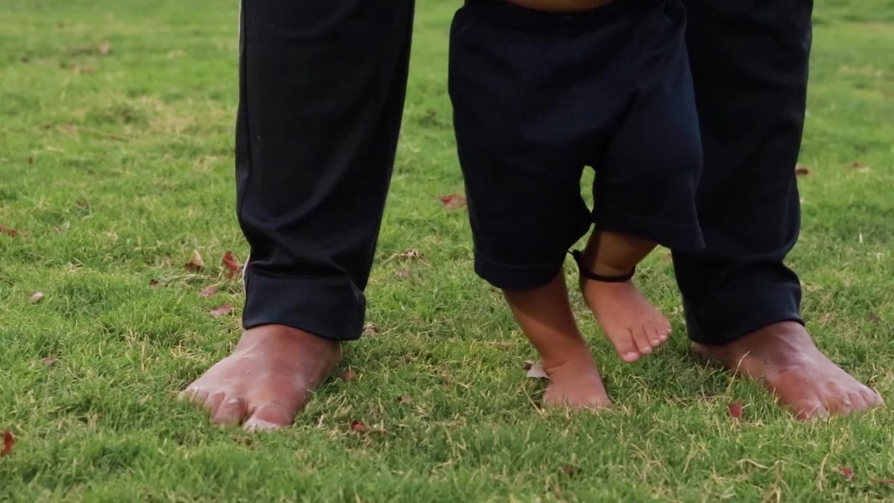 father helping son for walk at green grass at garden at evening