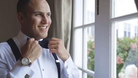 man adjusts his bowtie happily