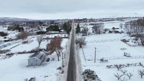 Toma-De-Drone-De-Una-Carretera-Arada-Que-Atraviesa-El-Campo-Rural-Lleno-De-Nieve.