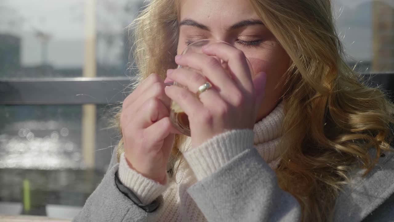 아침 햇살에 커피를 마시는 세련된 금발 여성의 클로즈업 샷