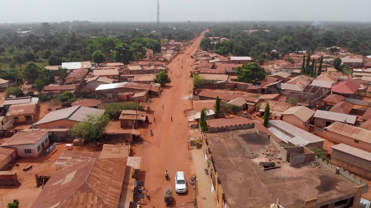 Ouidah, città del Benin, Africa occidentale, case lungo una strada sterrata africana non sviluppata, ripresa aerea con drone.