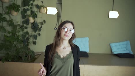 young dark hair female european student face looking at the camera saying no prohibits neutral and wearing elegant clothes and eyeglasses