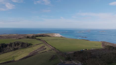 Flight-over-Herm-Island,-Channel-Islands-flying-north-with-Shell-Beach-in-distance-at-low-tide-with-clear-calm-sea