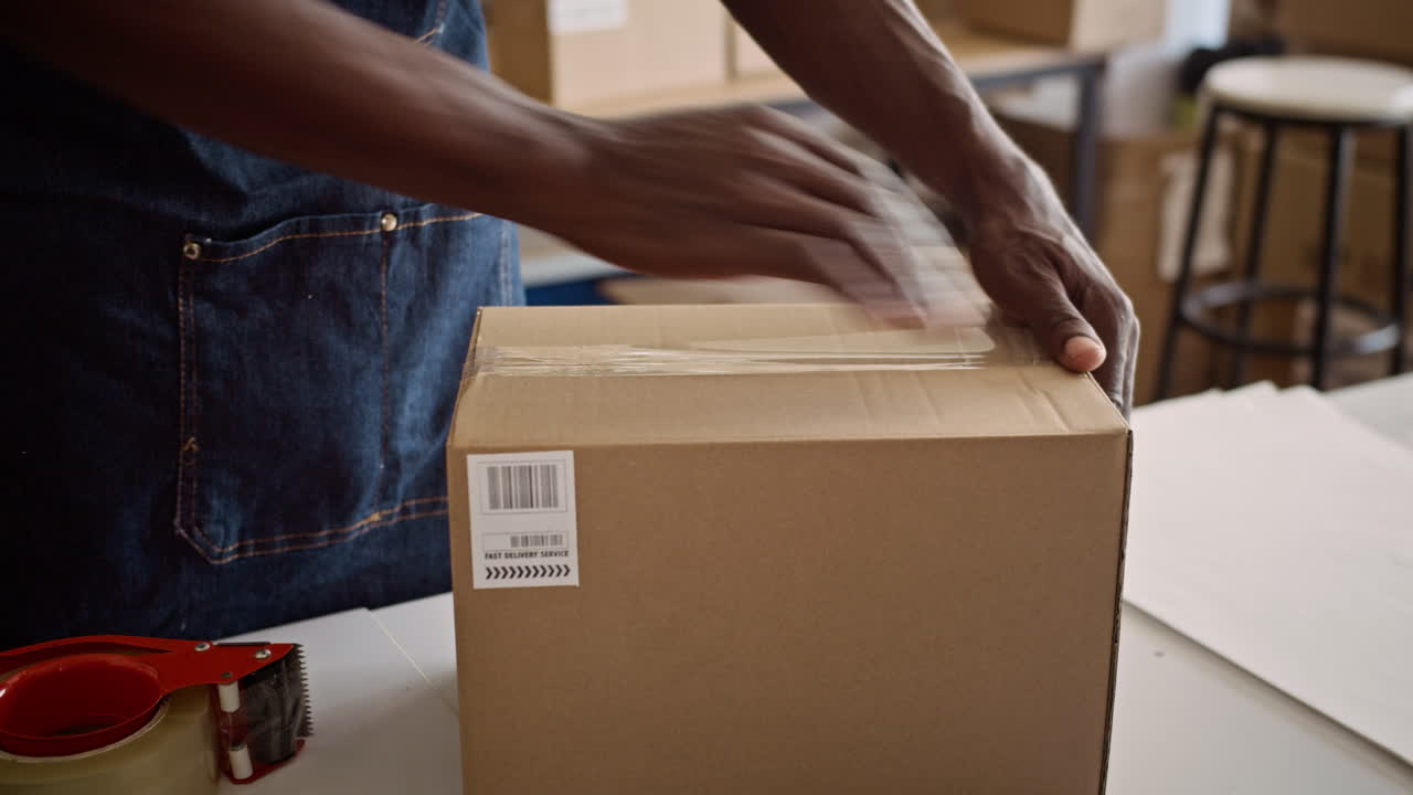 Hands of Worker Taping Box with Parcel before Shipping