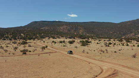 Aerial-tracking-fast-moving-car-down-remote-desert-road,-4K