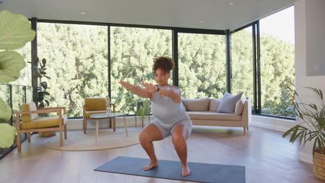 exercising on yoga mat, plus size woman doing squats in living room