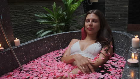 mujer relajándose en un baño de pétalos de rosa
