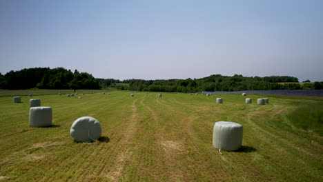 Montones-De-Heno-En-Envolturas-Blancas-En-El-Campo,-Vista-De-Drones