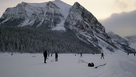 people playing ice hockey on the frozen lake louise, a glacier-fed alpine lake in banff national park in canada - medium shot