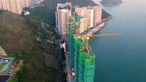 Sitio-De-Construcción-De-Un-Nuevo-Edificio-Con-Grúa-Cerca-Del-Agua-Durante-El-Día,-Vista-Desde-Un-Dron