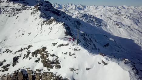 snowboarders aventureros disfrutando de la cima de una montaña en val thorens, alpes franceses - toma aérea de órbita rápida