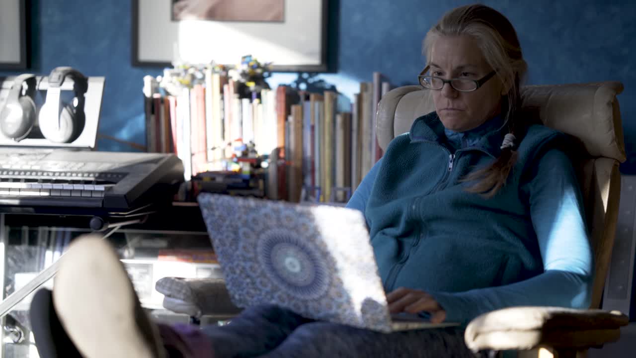 Woman using laptop in armchair indoors