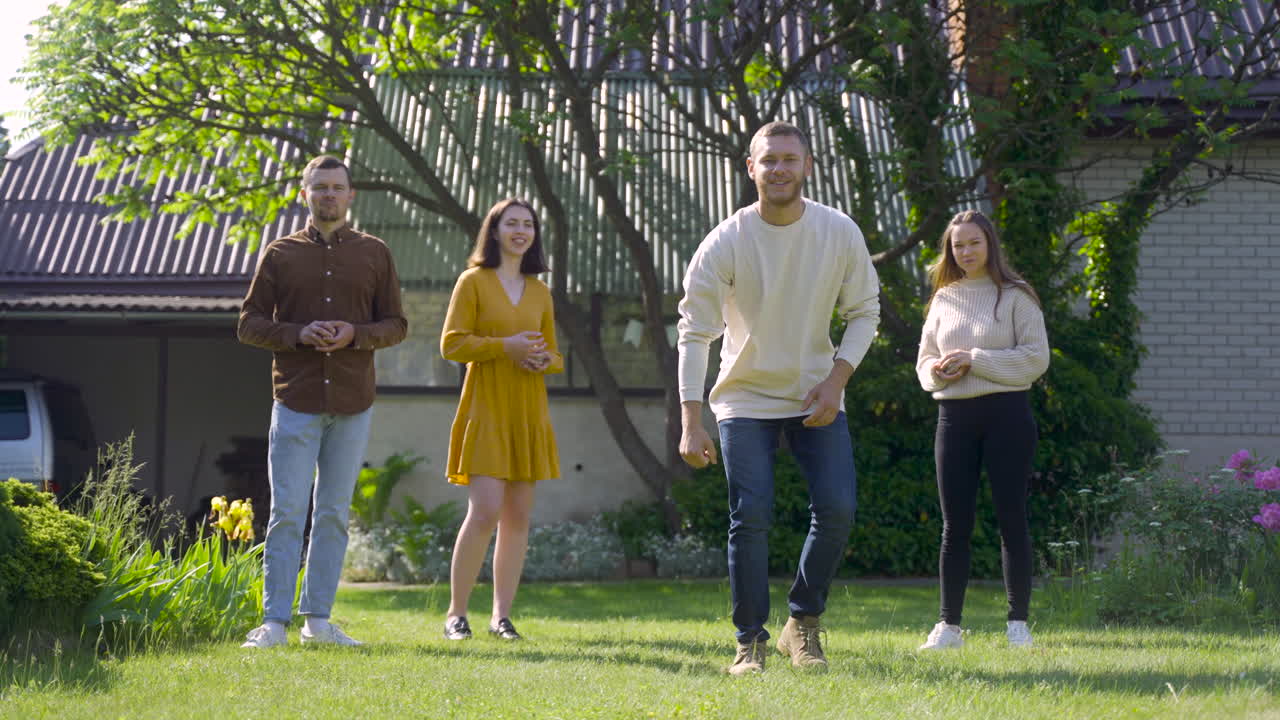 vista frontal de un joven caucásico en cuclillas y lanzando una pelota de petanca en el parque en un día soleado