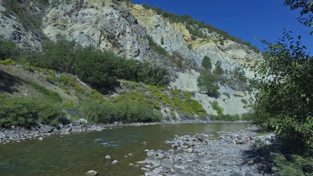 Crystal River flowing gently through a green valley under clear blue sky in Carbondale, Colorado, tilt down
