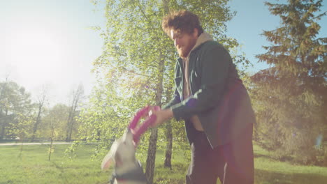 man lifting dog up in air while playing in park