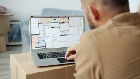 man reviewing a house floor plan on a laptop