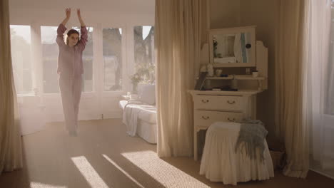 beautiful teenage ballerina girl practicing ballet dancing in bedroom rehearsing dance on weekend morning wearing pajamas at sunrise