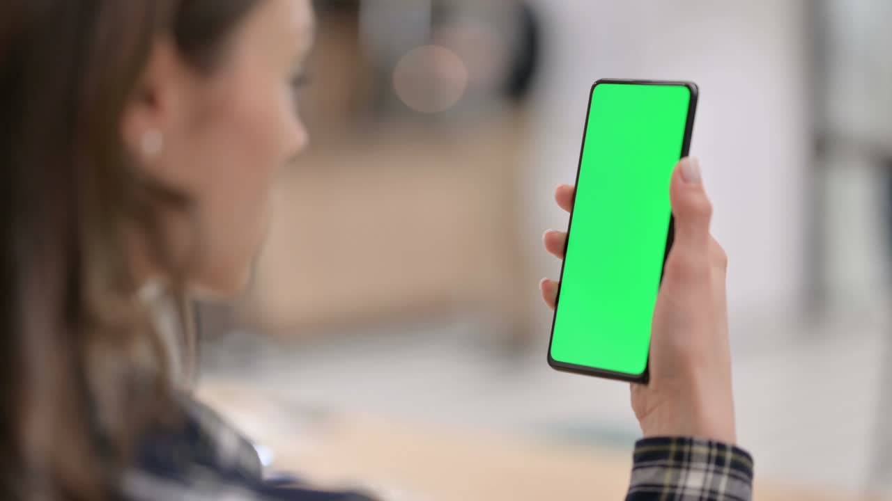 mujer mirando un teléfono inteligente con pantalla clave de croma verde