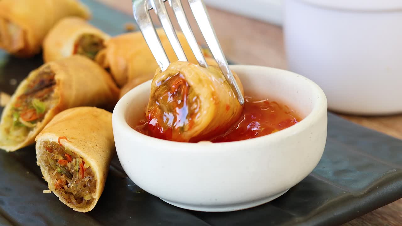 Spring roll dipped into sweet chili sauce