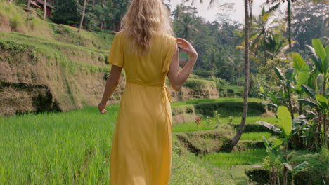 happy woman walking in rice paddy wearing yellow dress enjoying vacation exploring exotic cultural landscape travel through bali indonesia