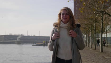 Confident-stylish-blonde-woman-struts-along-the-pier-in-the-morning-sun