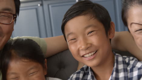 slow motion shot as family group sit on sofa and laugh