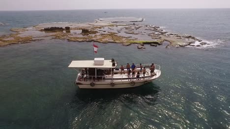 lebanon flag on tourist boat in byblos beach, aerial circle pan