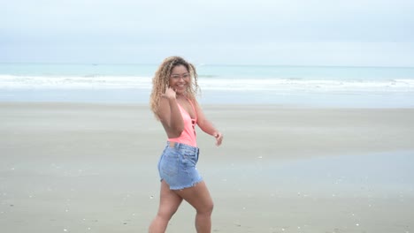 curly latina walking over the beach and waving "come here"