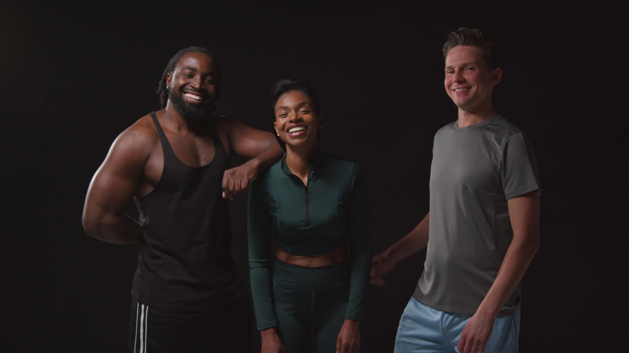 retrato de estudio de un grupo de atletas masculinos y femeninos sonrientes en entrenamiento de ropa de fitness disparado contra un fondo negro