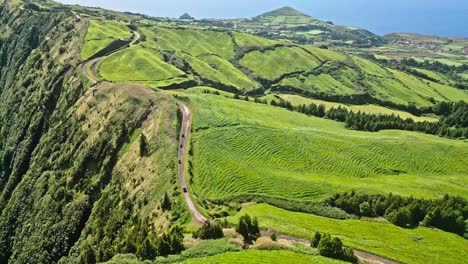 Lush-green-hills-with-a-winding-road-on-a-sunny-day-in-the-Azores,-Portugal