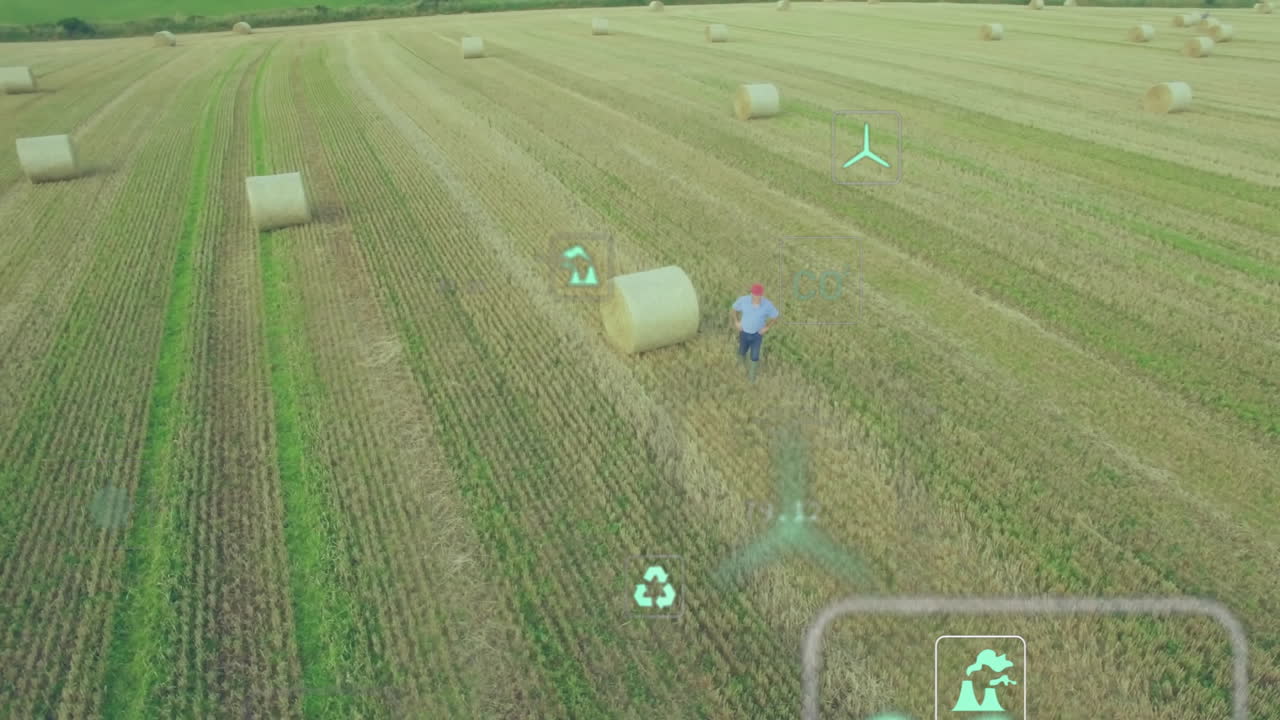 Male farmer standing next to hay bale on harvested field, monitoring smart farming AR overlays