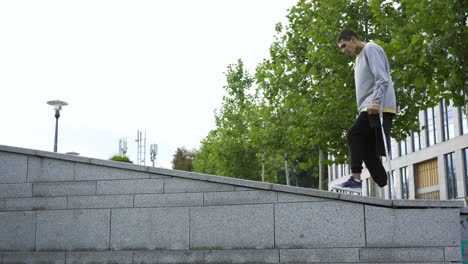 man with one leg on crutches doing a flip in the street.