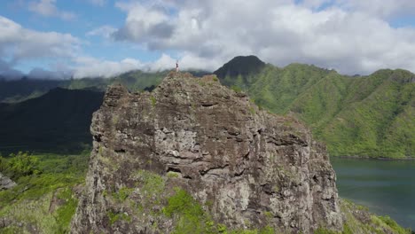 Mujer-Viajera-Se-Encuentra-En-La-Roca-Del-León-Agachada-En-Hawaii,-Revelación-Aérea-De-La-Playa