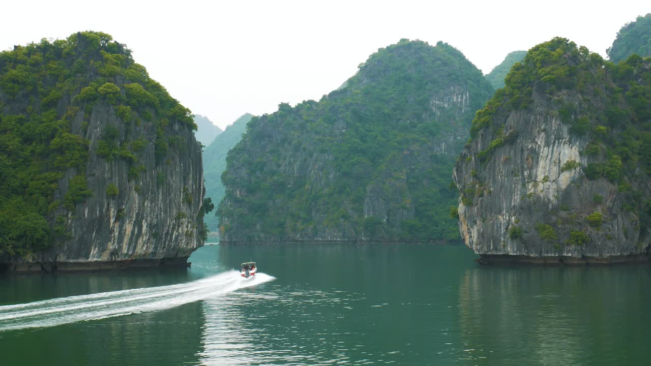 하롱 만 에 있는 석회암 섬 들 을 가로질러 속도 보트 경주